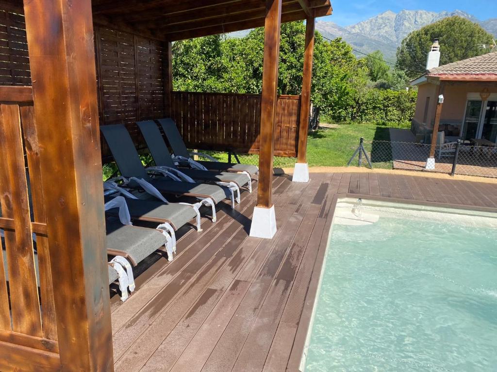 a row of lounge chairs on a deck next to a swimming pool at La Lagunilla Golf in Candeleda