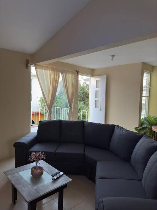 ein Wohnzimmer mit einem blauen Sofa und einem Tisch in der Unterkunft Departamento completo, cómodo y cerca del aeropuerto in San Agustin de las Juntas