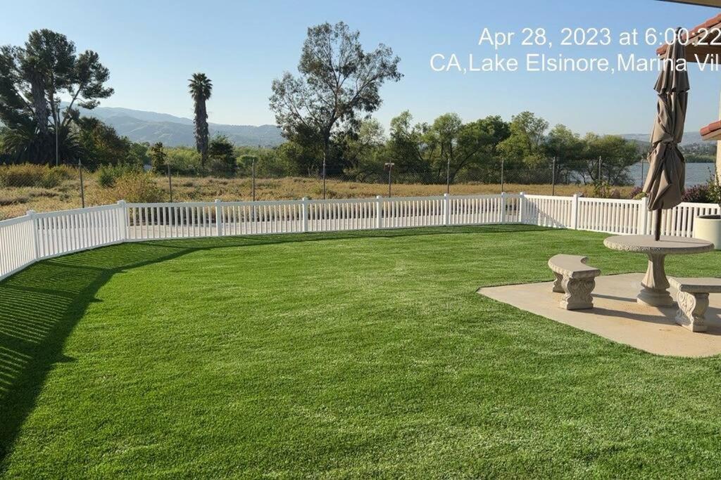 a large yard with a white fence and a bench at Amazing Lakefront Home with a Private Beach in Lake Elsinore