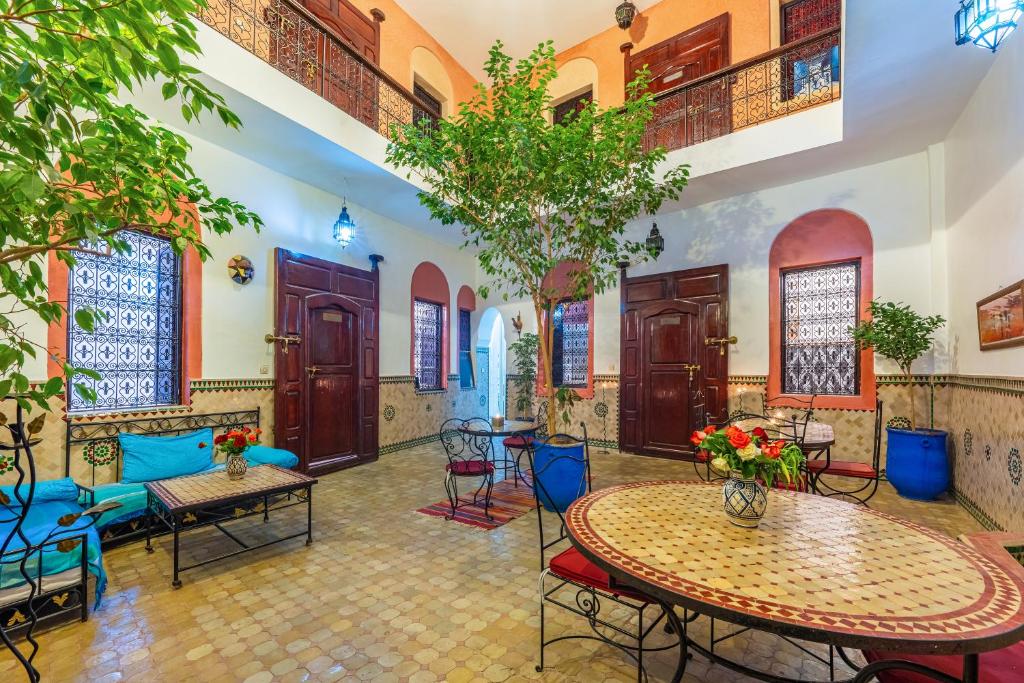 una sala de estar con mesas, sillas y árboles en Riad Todra, en Marrakech