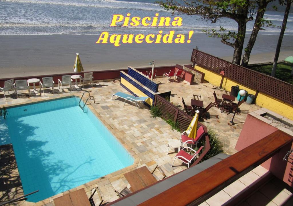a swimming pool next to a beach and the ocean at Pousada Casa na Praia in Ubatuba