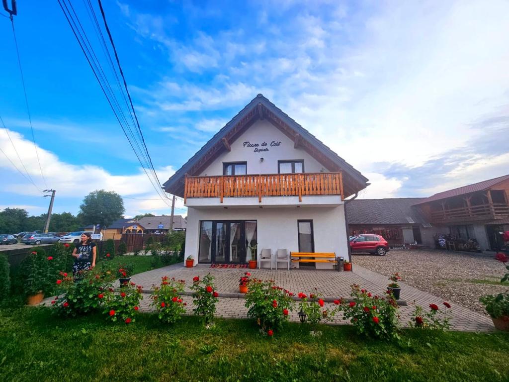 een klein wit huis met een balkon en een aantal bloemen bij Floare de Colt Sapanta in Săpînţa
