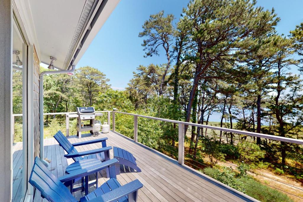a deck with blue chairs and a grill on it at Drummer Cove Retreat in Wellfleet