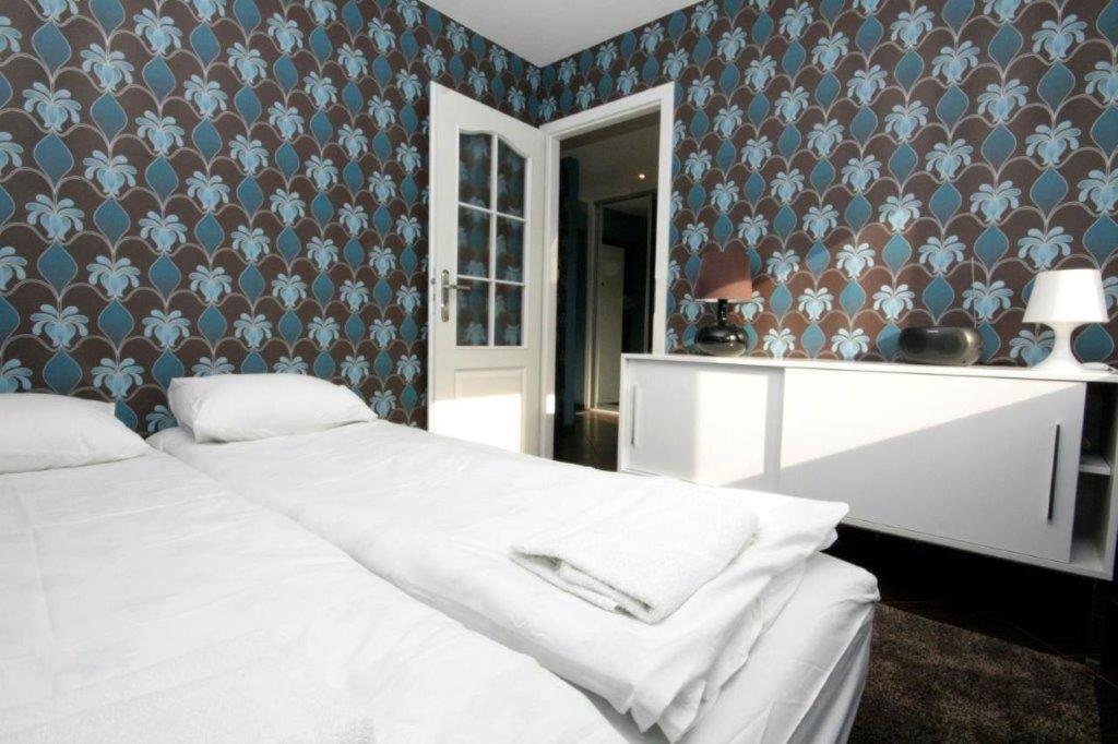 sypialnia z białym łóżkiem i niebieską ścianą w obiekcie Pomorskie Apartamenty Mazurska w Gdańsku
