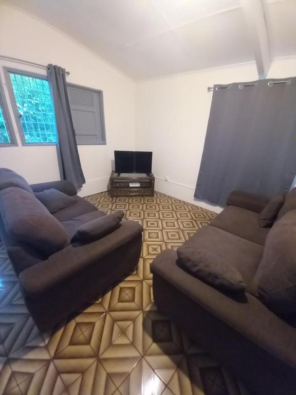 una sala de estar con 2 sofás marrones y una ventana en Eskal des berges, en Bras-Panon