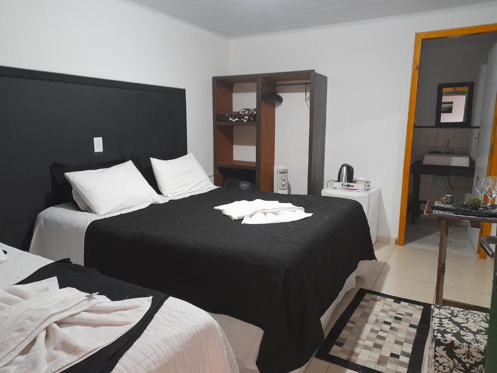 1 dormitorio con 2 camas con sábanas negras y almohadas blancas en Entre serra pousada de altitudes, en Urubici