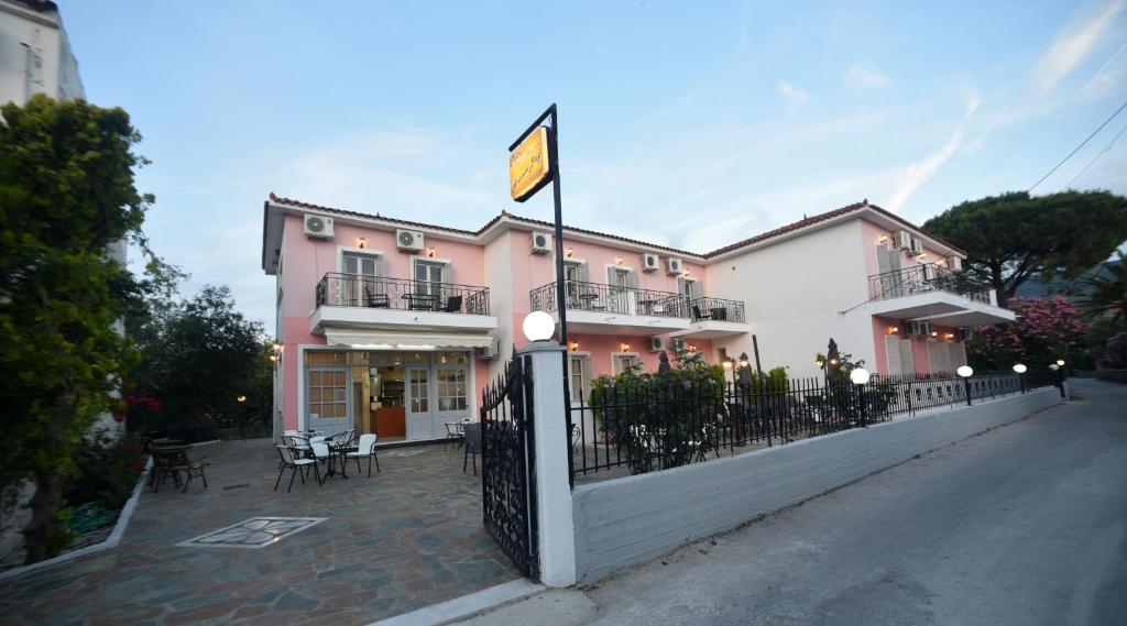 un edificio rosa y blanco con mesas y sillas en Anaxos Bay Rooms & Apartments, en Anaxos