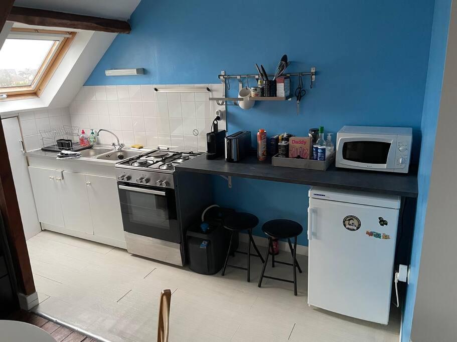cocina azul con fogones y microondas en Donville vue sur la mer, en Donville-les-Bains