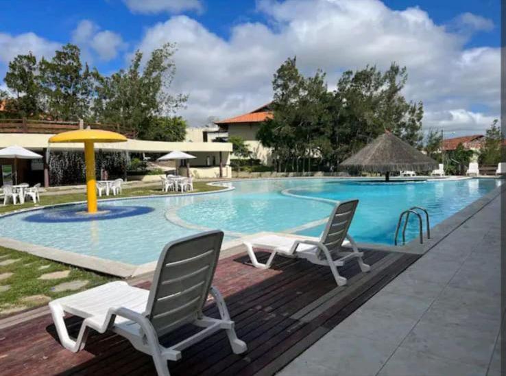 格雷夫森德的住宿－FLAT NA FAZENDA MONTE CASTELO GRAVATÁ - Pe，一个带两把椅子和遮阳伞的游泳池