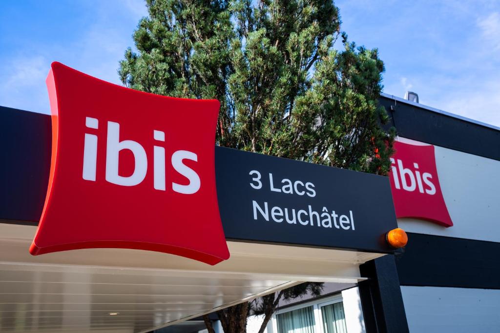 ein Schild auf der Gebäudeseite in der Unterkunft ibis 3 Lacs Neuchâtel in Thielle