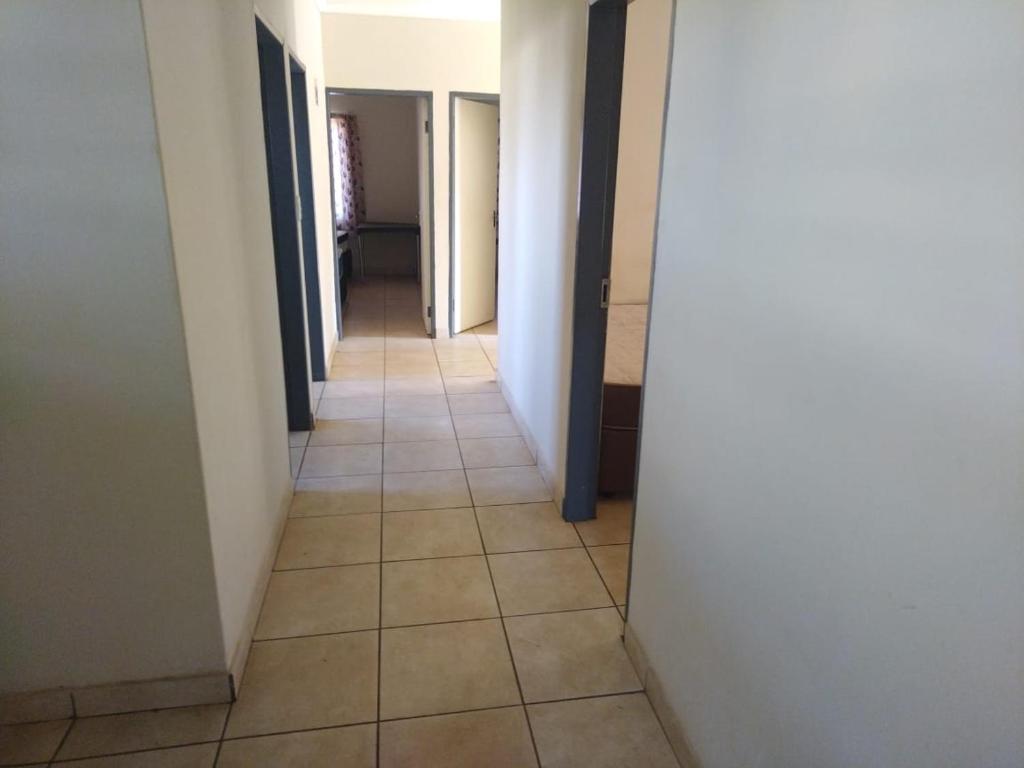 a hallway with white walls and a tile floor at KUNGWINI ACADEMY CENTRE in Erasmus