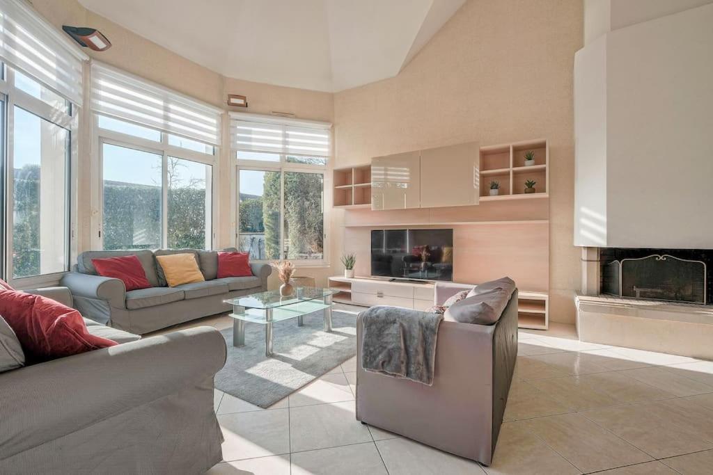 ein Wohnzimmer mit zwei Sofas und einem Kamin in der Unterkunft Villa Paris Garden - 15 minutes de Disneyland Paris in Montévrain