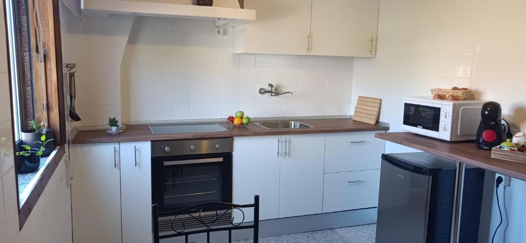 a kitchen with white cabinets and a sink and a microwave at A Niñada in Marín