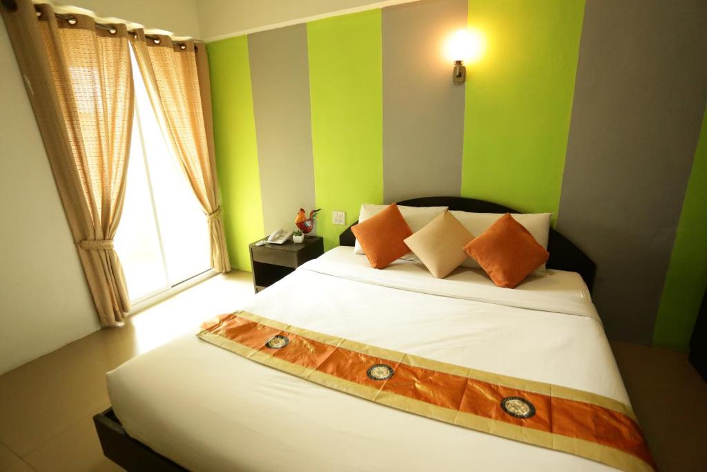 Un dormitorio con una cama con paredes verdes y una ventana en Puangpech Place en Lampang