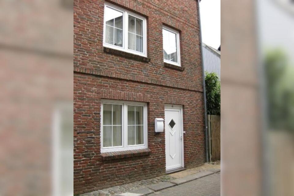 een stenen huis met een witte deur en ramen bij Ferienhaus Flensburg Sandberg in Flensburg