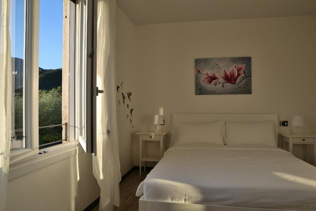 a white bedroom with a bed and a window at Alla Favorita in Bassano del Grappa