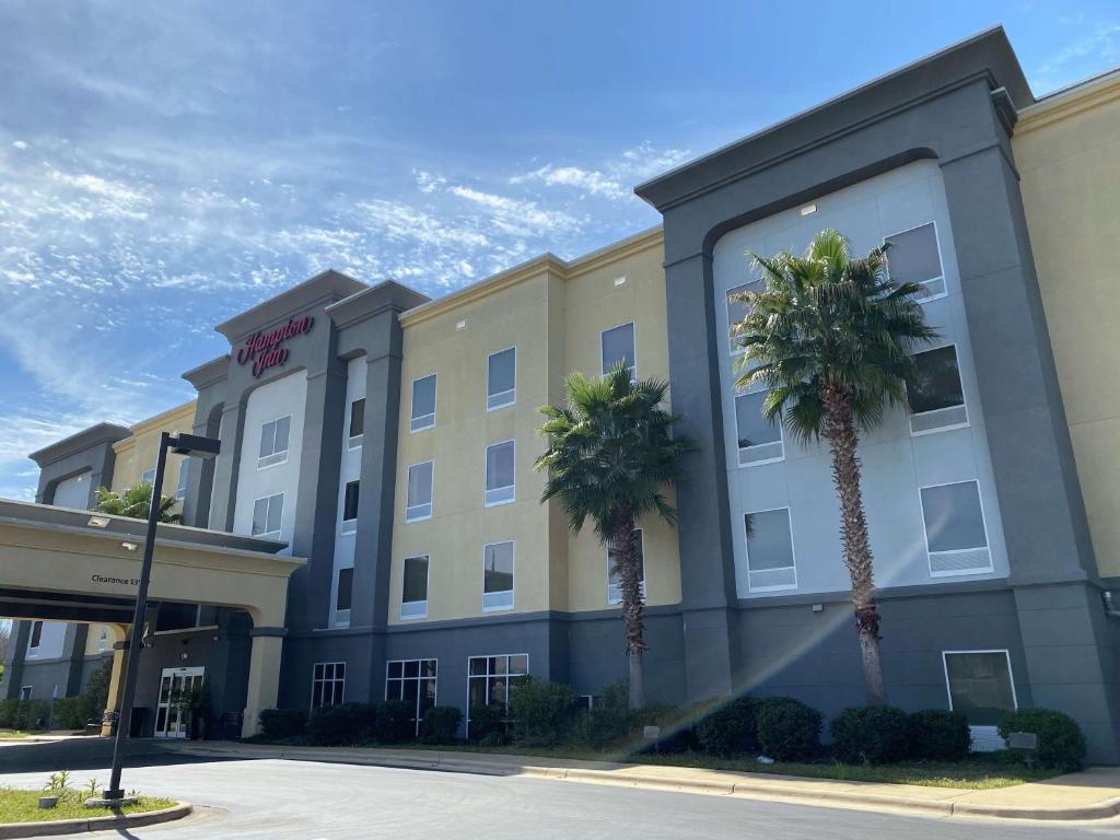 un hotel con palme di fronte a un edificio di Hampton Inn by Hilton Leesville Fort Johnson a Leesville