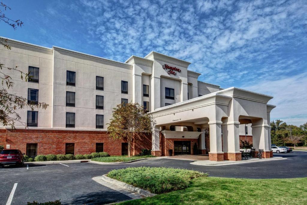 Hampton Inn Jacksonville في جاكسونفيل: مبنى أبيض كبير مع موقف للسيارات