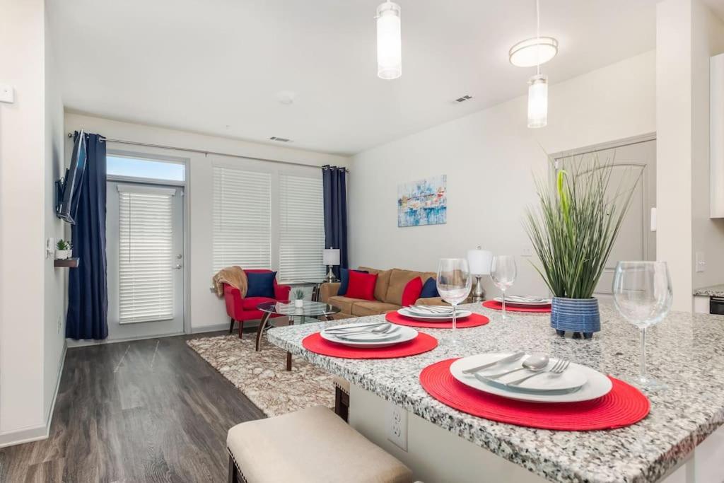 uma cozinha e sala de estar com uma mesa com placas vermelhas em Luxe Suite-King Bed-Fast WiFi-6mi to CLT em Charlotte