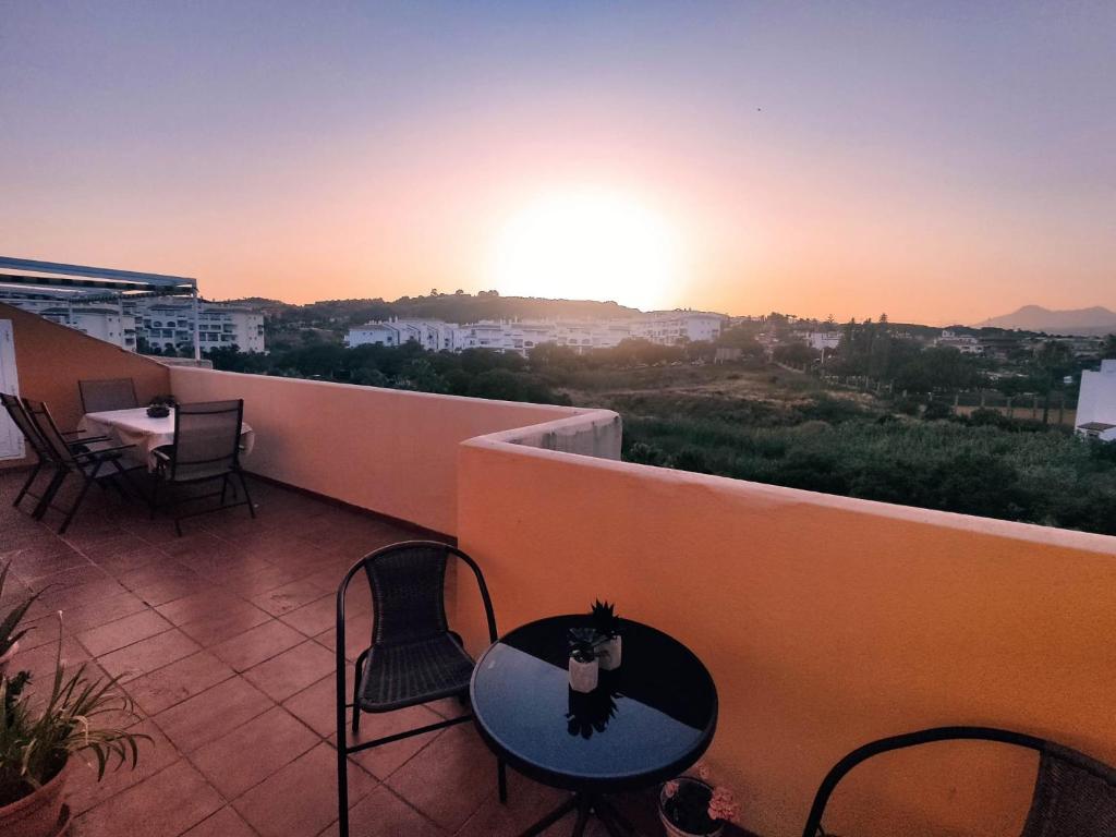 eine Katze, die auf einem Tisch auf einem Balkon sitzt und den Sonnenuntergang beobachtet in der Unterkunft Ático - CENTRO de Sabinillas - Calle la Pasionaria - in San Luis de Sabinillas