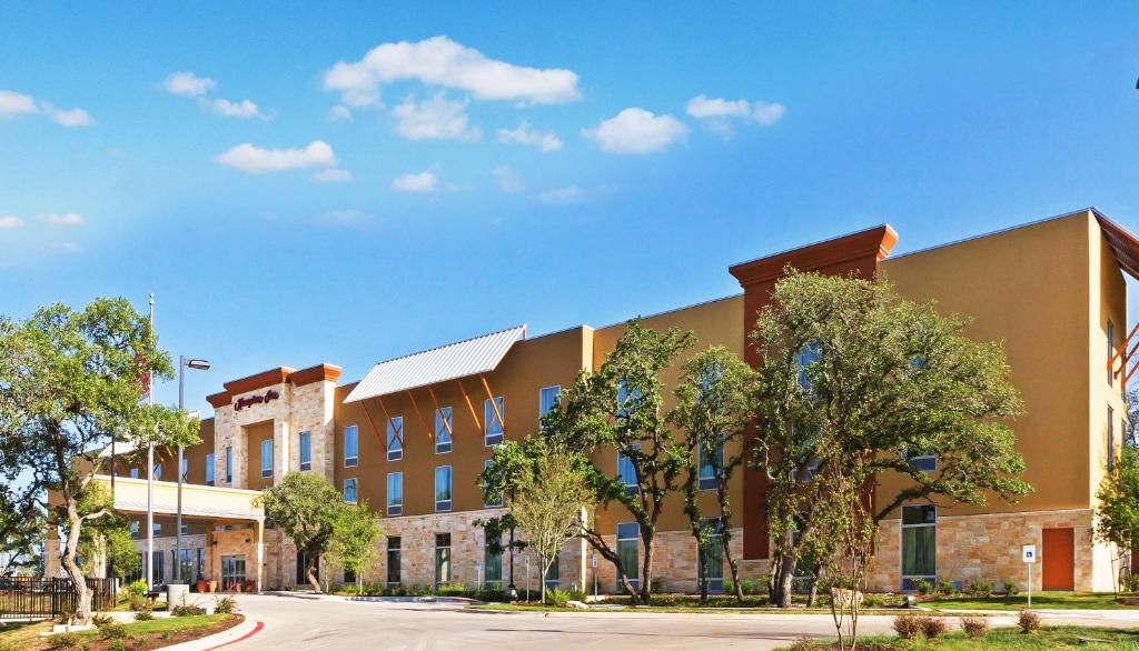 a large building with trees in front of a street at Hampton Inn Austin Oak Hill in Austin