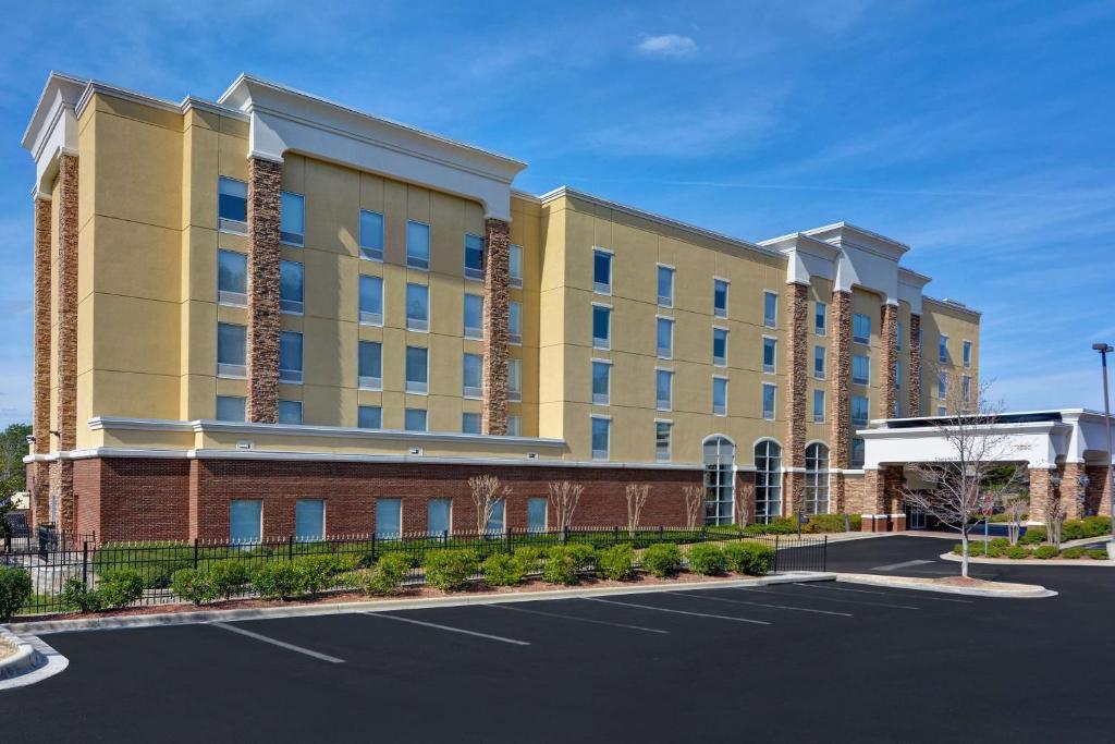 Hampton Inn & Suites Birmingham-Hoover-Galleria في هوفر: مبنى أصفر كبير مع موقف للسيارات