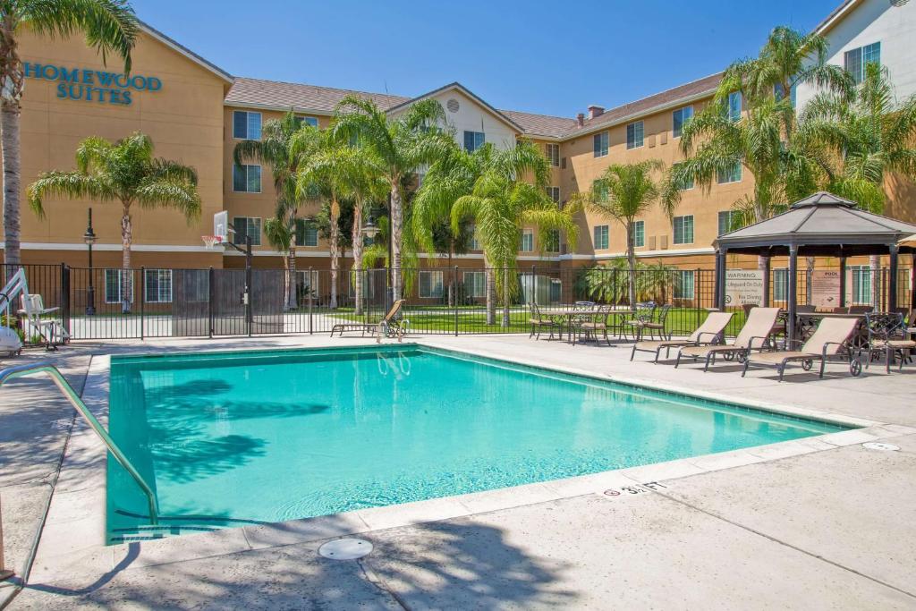 a swimming pool in front of a hotel with palm trees at Homewood Suites Bakersfield in Bakersfield