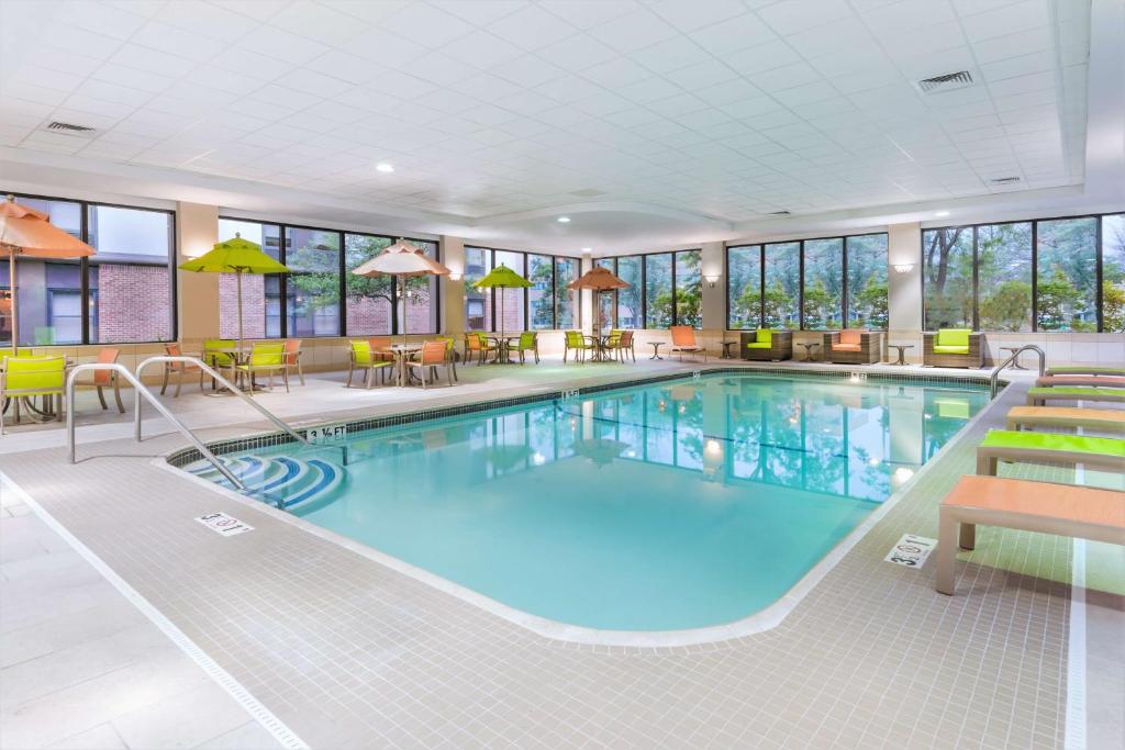 Una piscina en una habitación de hotel con mesas y sillas. en Hampton Inn Boston &#47; Marlborough, en Marlborough