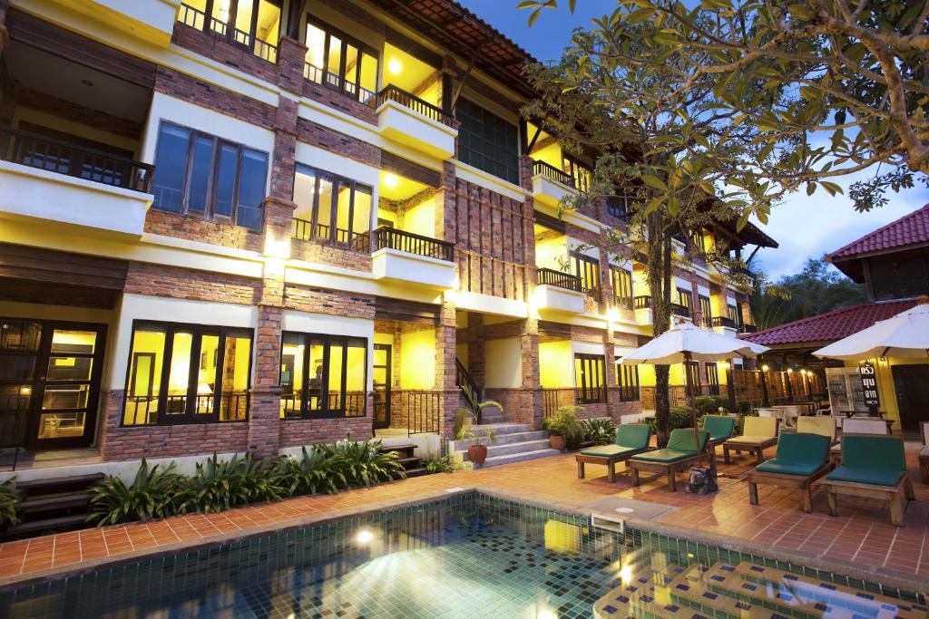 a hotel with a swimming pool in front of a building at Motive Cottage Resort in Khao Lak