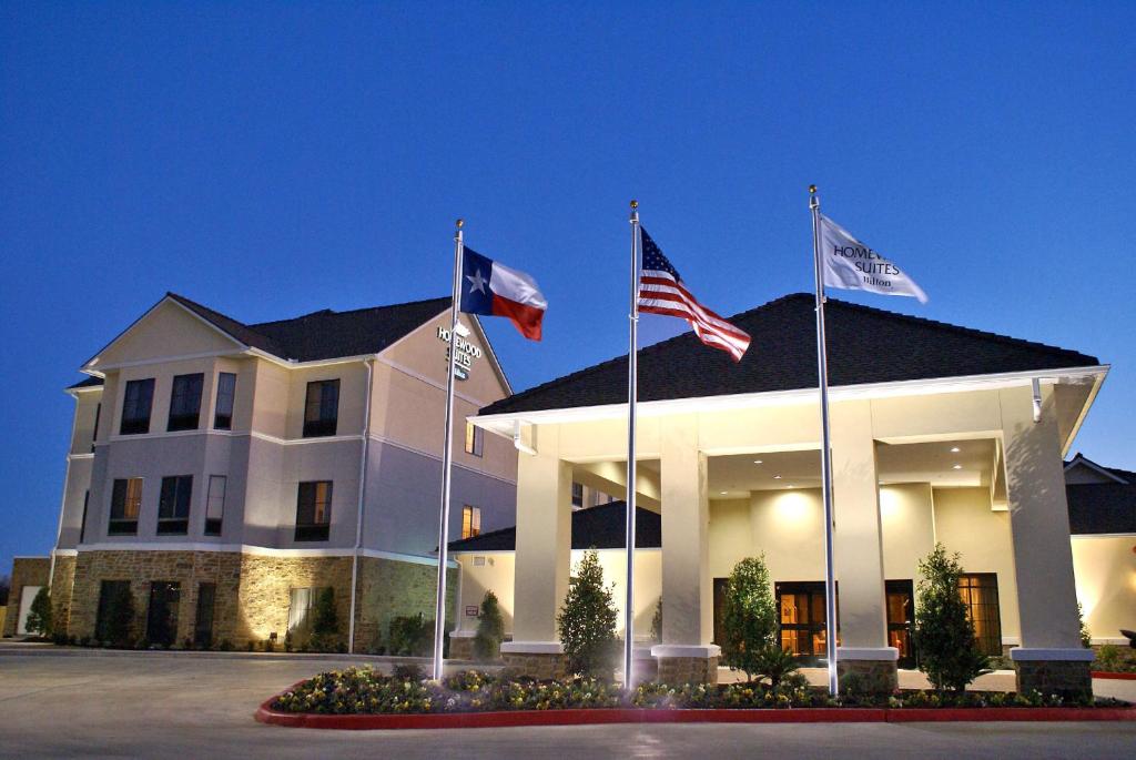 tres banderas volando delante de un edificio blanco en Homewood Suites Beaumont, en Beaumont