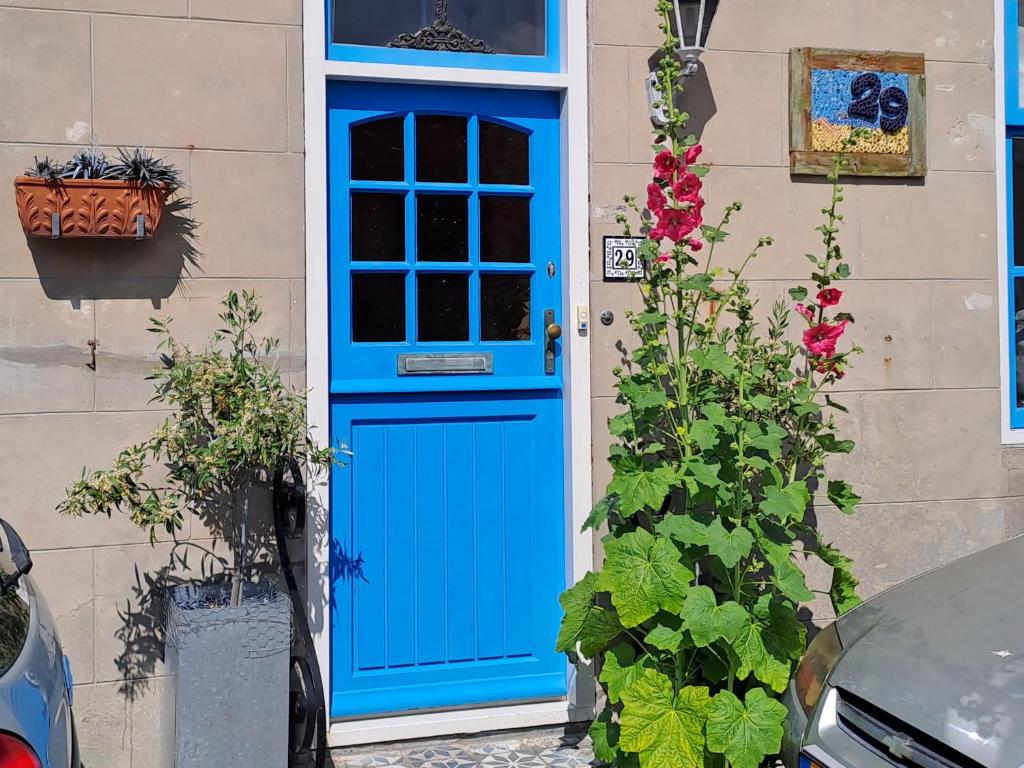 a blue door on the side of a house with flowers at Unia's Verhuur in Zoutelande