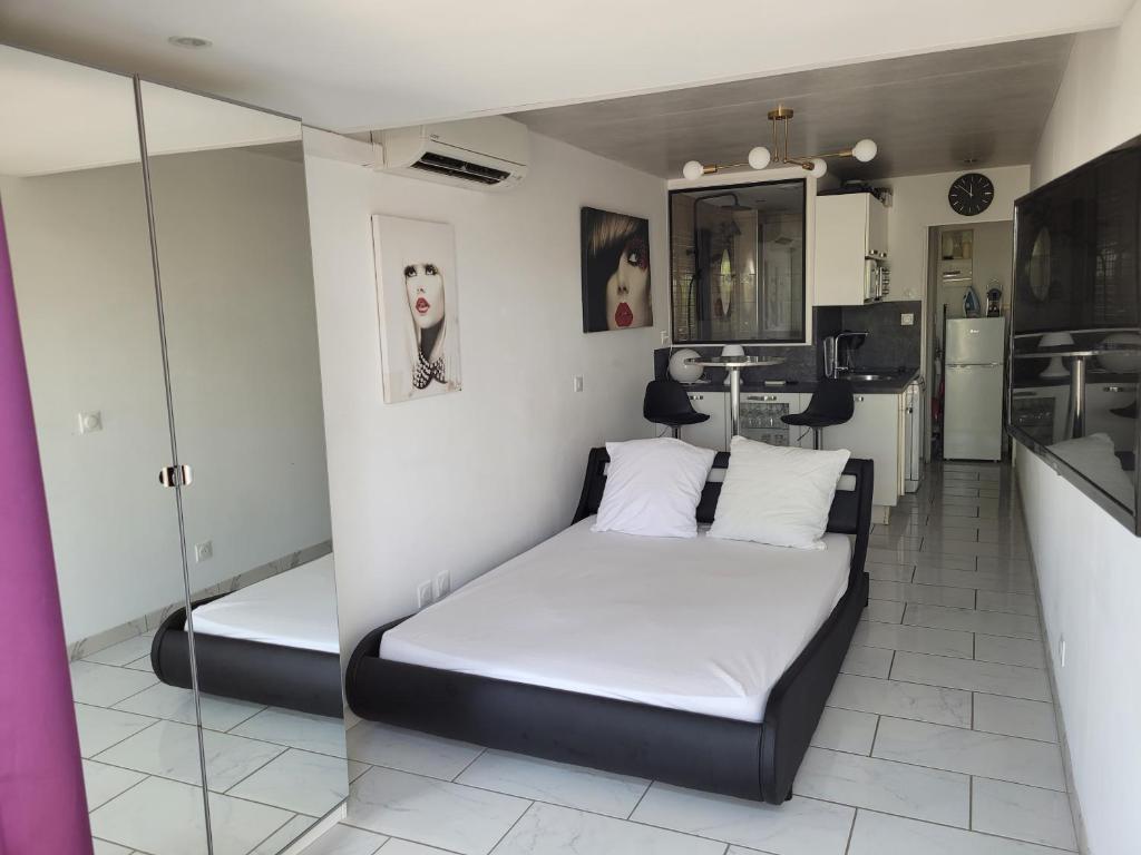 une chambre avec un lit avec des draps blancs et une cuisine dans l'établissement PORT NATURE 2 Village Naturiste, au Cap d'Agde