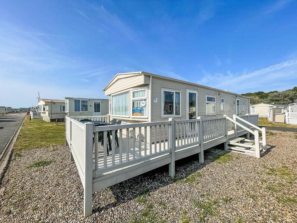 a tiny house with a white fence next to a street at Spacious Caravan For Hire With Decking By The Beach In Suffolk Ref 40094nd in Lowestoft