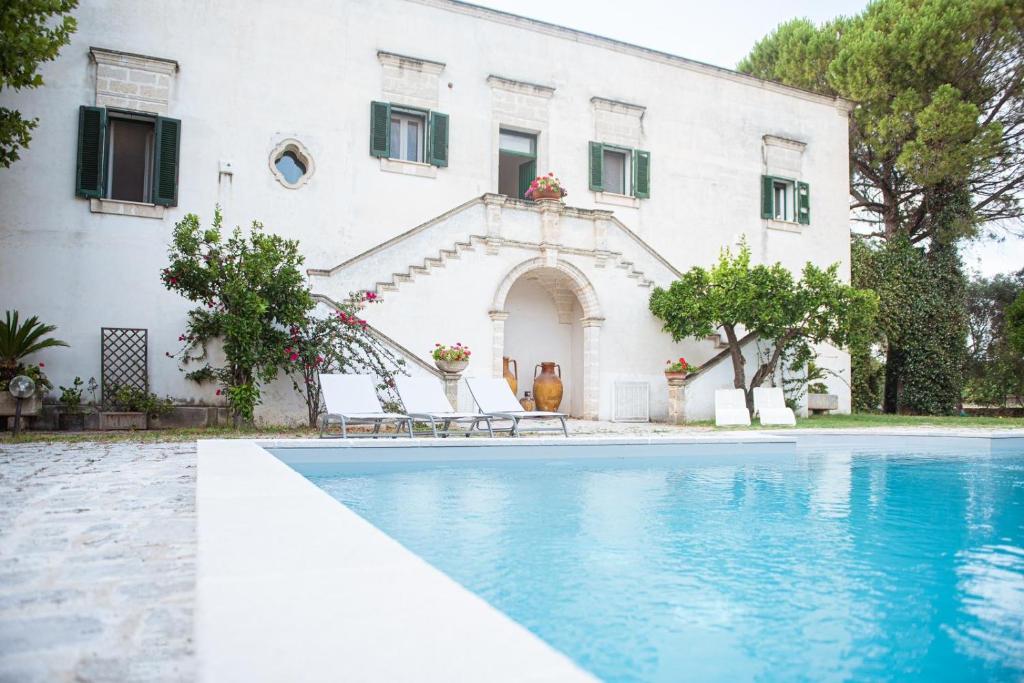 una casa con piscina frente a un edificio en Villa Encantamiento - Dimora Gelsomino - Masseria Storica nel cuore della Puglia con piscina, en Latiano