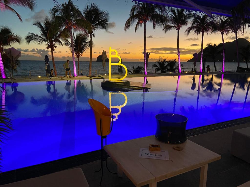 a table next to a swimming pool with a sunset at Koala Room in Le Diamant