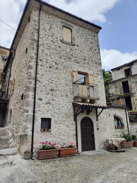 duży kamienny budynek z balkonem i kwiatami w obiekcie Monolocale rustico di Ariola w mieście Cansano