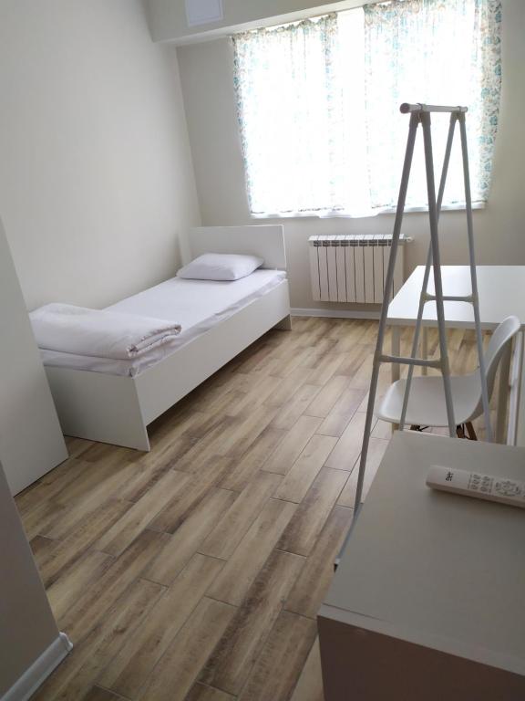 1 dormitorio con 1 cama y suelo de madera en Leo, en Atyraū