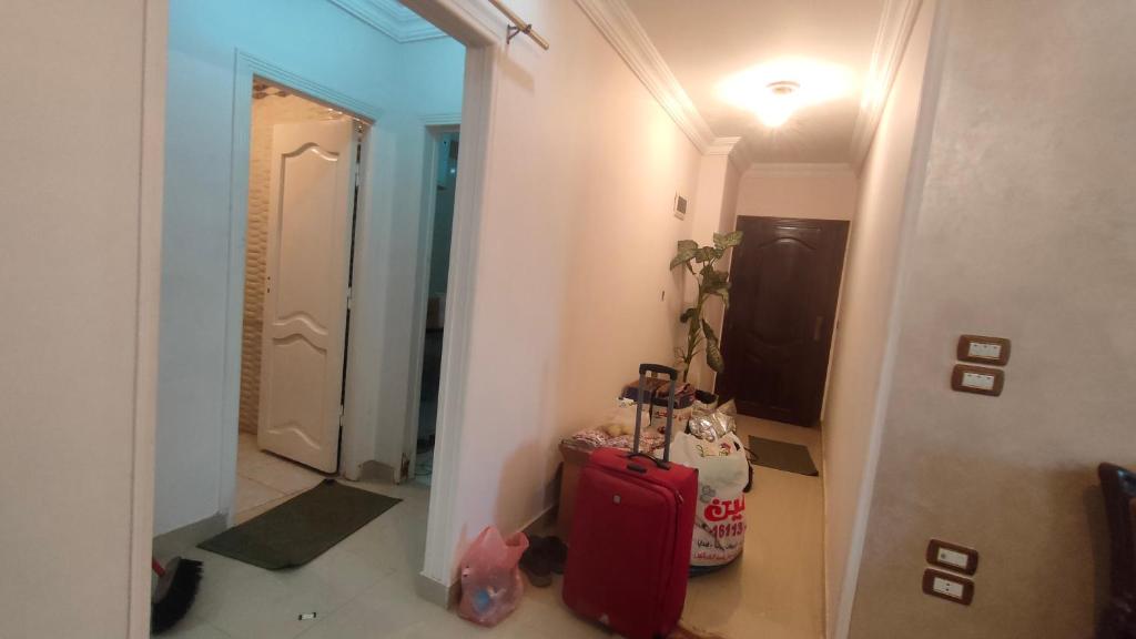 um corredor com uma mala vermelha e um espelho em شقة مفروشة بالكامل بالإسكندرية تانى صف بحر em Alexandria