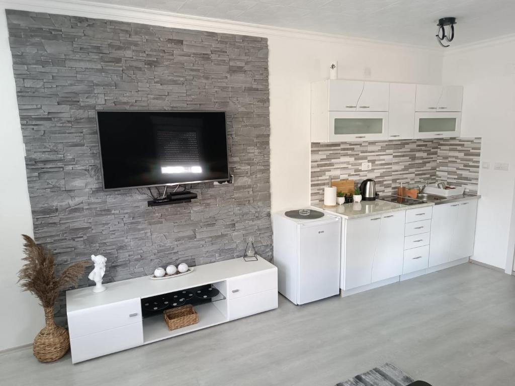 a kitchen with white cabinets and a tv on a brick wall at ATOS in Belgrade