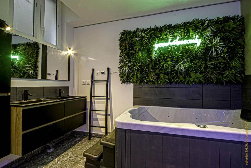 La salle de bains est pourvue d'une baignoire et d'un mur vert. dans l'établissement CosyRouen Bali Spa Hamman, à Rouen