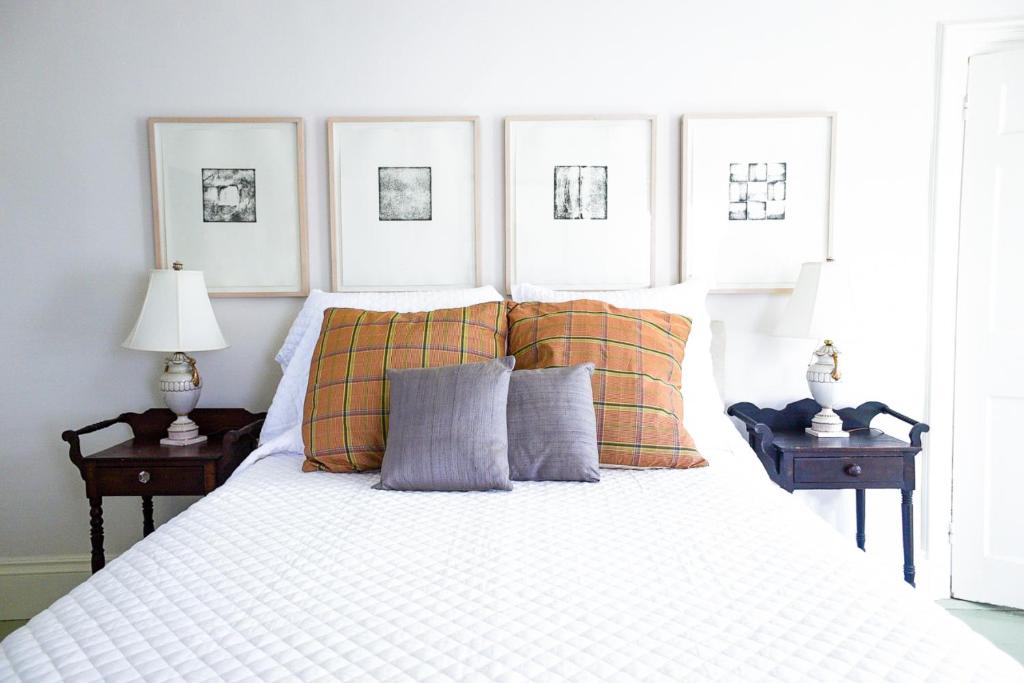 a bedroom with a white bed with orange pillows at The Waldoboro Inn Room 3 in Waldoboro