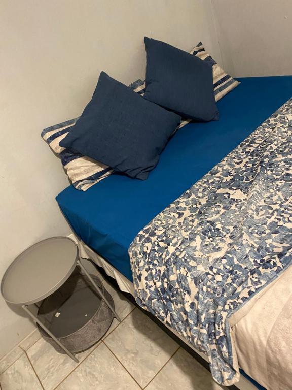 1 cama con sábanas azules y almohadas azules en Alvin's House, en Tsumeb