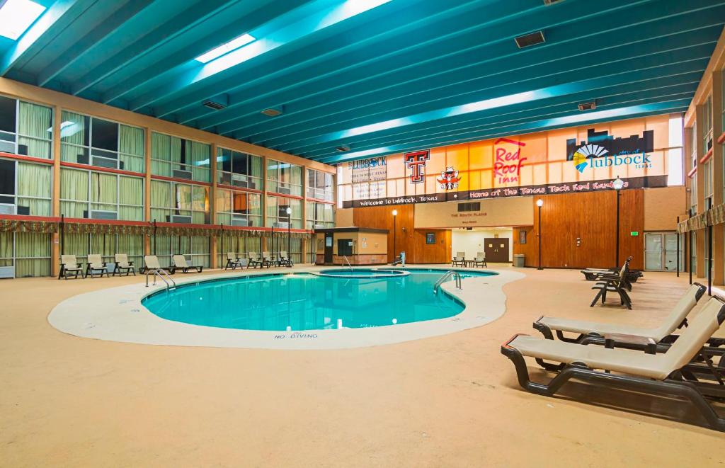 una gran piscina en un gran edificio con sillas en Red Roof Inn Lubbock, en Lubbock