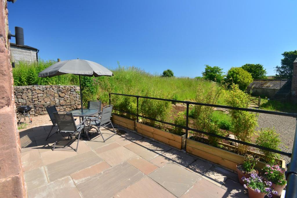 un patio con mesa, sillas y sombrilla en Scottish countryside Bothy, en Arbroath