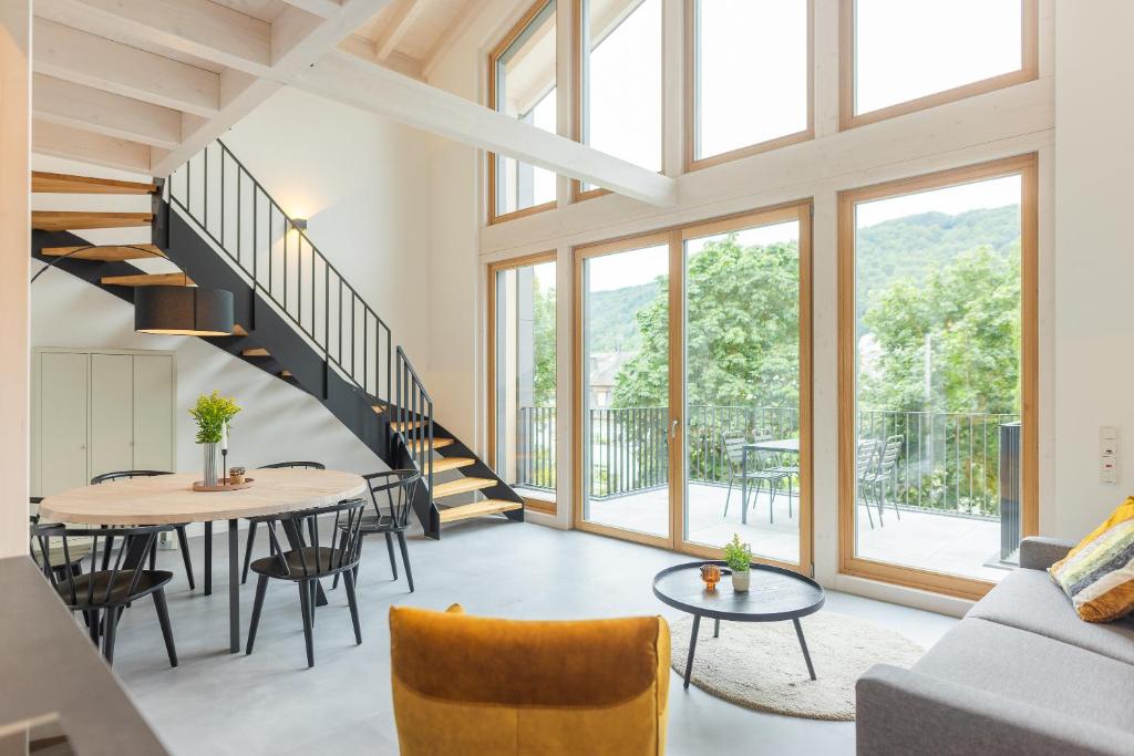 a living room with a staircase and a table and chairs at Ferienhaus MOSELLODGE in Enkirch