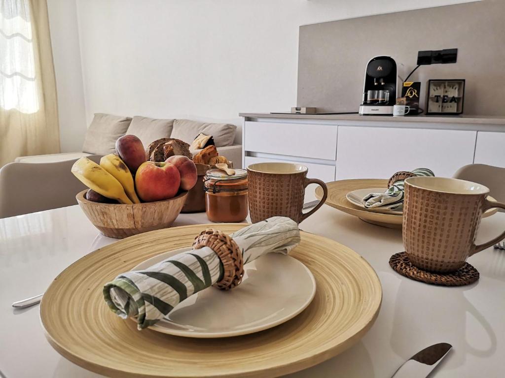 a table with plates and cups and a bowl of fruit at Apartamentos Mares de Lava - Playa Blanca in Playa Blanca