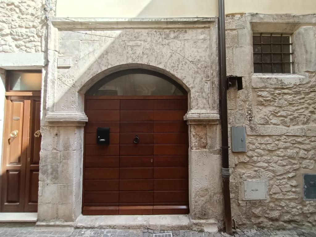 una puerta de madera en un edificio de piedra con un arco en La casetta di Bianca en Sulmona