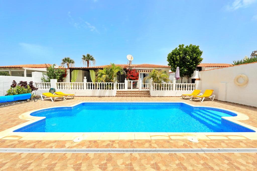 a swimming pool in a yard with chairs and a house at Villa Sofia in Callao Salvaje in Callao Salvaje
