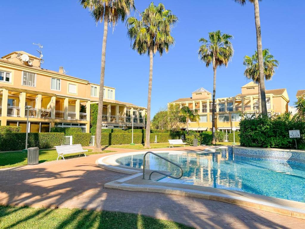 a swimming pool with palm trees in front of a building at Apartamento les Marines in Denia