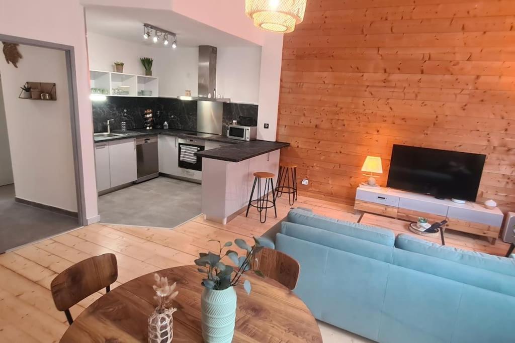 un salon avec un canapé bleu et une cuisine dans l'établissement Le Bon appart, à Marlens